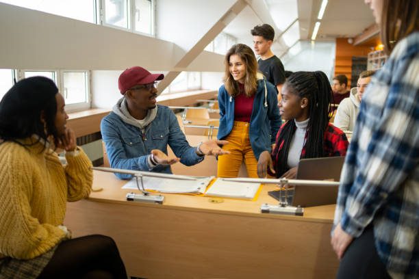Teenage students learning together as they group around a desk to share their thoughts in a university classroom