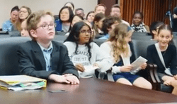 Students sitting at lawyers table and in the audience at a mock trial.